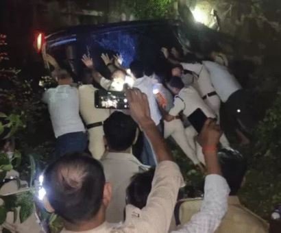 कार के नीचे से कांवड़ियों को निकालते पुलिसकर्मी