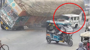 A truck loaded with straw overturned on a Bolero in Rampur