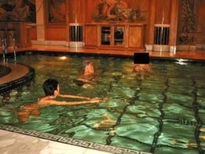 पूर्व अमेरिकी राष्ट्रपति बिल क्लिंटन एक स्विमिंग पूल में 2 महिलाओं के साथ