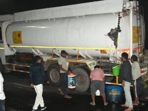 ड्रम, बाल्टी, पीपे में पेट्रोल भरते लोग